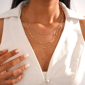Detail of layered gold and silver mixed metal necklace with small oval beads on a model