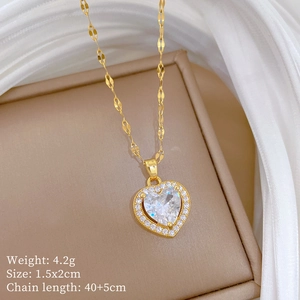 Detail of gold heart pendant with cubic zirconia inlay on beige jewelry stand