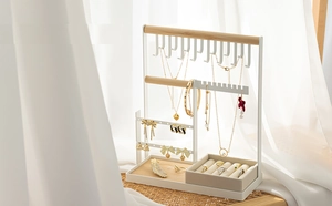 Close-up of white jewelry organizer with wooden bars and rings displayed on a tray