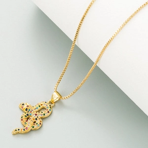 Detailed macro view of a golden snake pendant necklace featuring vibrant colorful zircon stones
