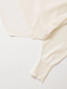 Detail of ribbed cuffs on a cream white lightweight knit sweater with sheer texture