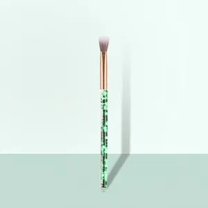 Detail of eyeshadow blending brush with green glitter handle and rose gold metal ferrule