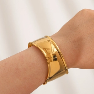 Close-up of a wide polished gold cuff bracelet worn on a wrist for a modern look