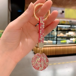 Macro detail of sparkling crystal ball keychain with rhinestone-studded strap and gold clasp