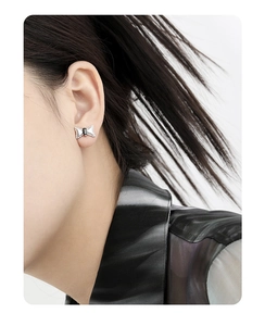 Close-up of a silver bow earring with a black stone worn on a female ear