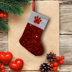 Red sequin Christmas stocking with grey plush cuff and paw embroidery on rustic wood background