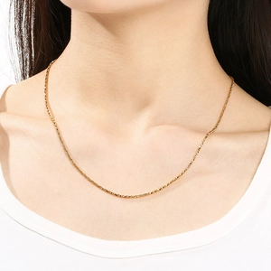 Collier chaîne torsadée dorée en acier inoxydable porté par un mannequin au style épuré