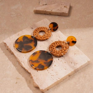 Bohemian rattan earrings with vintage tortoise resin discs on marble stone display