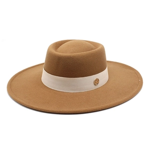Detailed view of the brown wool felt fedora with beige ribbon and golden metal logo