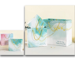 Detail of teal watercolor gift bags with gold vein patterns and braided rope handles