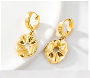 Detailed close-up of golden irregular hoop earrings with textured pleated finish and hollow center