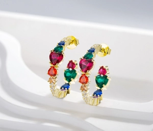 Macro detail of 925 silver hoop earrings with heart-shaped multi-color zircons