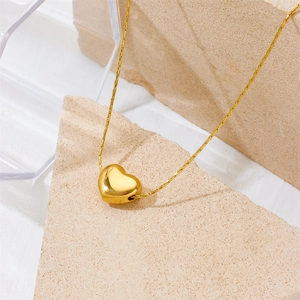 Golden heart pendant necklace in titanium steel on minimalist aesthetic background