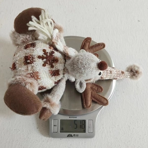 Knitted reindeer plush ornament weighing 518g on a digital kitchen scale for measurement