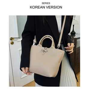 Detail of nude lychee pattern leather bucket bag with metallic T-shaped buckle