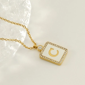Vue macro du pendentif carré plaqué or 18K avec la lettre C et incrustation