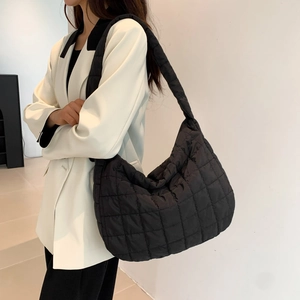 Detail view of the black quilted puffer tote bag on a model for daily commute style