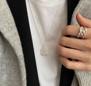 Close-up of 925 sterling silver chunky chain ring and retro coin pendant on model