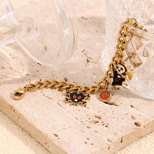 Detail view of 18K gold plated Cuban chain bracelet with Halloween pumpkin and skull charms