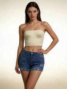Front view of slim fit denim shorts with frayed edges paired with a beige corset top