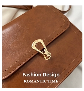 Close-up of brown leather handbag with gold irregular clasp and neat stitching detail
