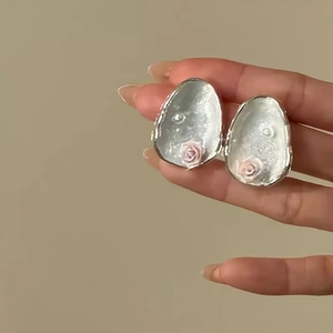 Detailed close-up of a silver egg-shaped trinket box with pink rose relief carving