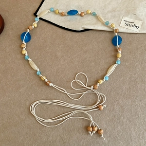 Detail of bohemian waist chain with acrylic resin and wooden beads on woven cord