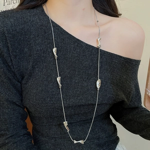 Detail view of a silver Y2K long necklace with irregular liquid metal geometric pendants