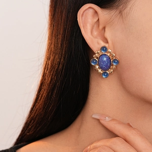 Macro view of French vintage gold earrings with oval blue enamel and silver pins