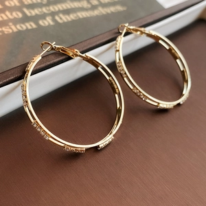 Macro shot of gold double hoop earrings with pavé cubic zirconia on wooden background