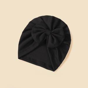 Detailed texture of black knitted baby turban hat with a large bow decoration