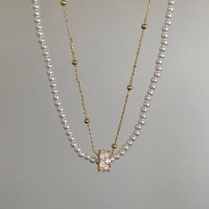 Détail du collier double rang avec perles blanches et pendentif cylindre serti de cristaux