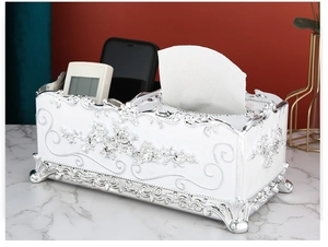 Detailed view of white tissue box with silver floral carving and functional storage slots