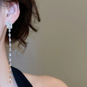 Close-up of elegant silver tassel earrings with rectangular cubic zirconia on a model