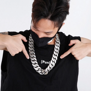 Close-up of chunky silver stainless steel Cuban link necklace worn by a male model