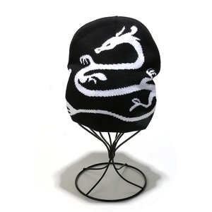 Detailed close-up of a black knit beanie with a white dragon jacquard pattern