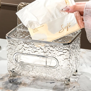 Detail einer Hand beim Einlegen von Tüchern in die transparente Wellenbox mit Silberfüßen