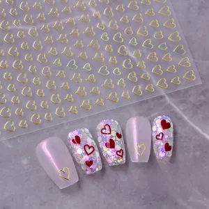 Detail of gold hollow heart nail stickers showing application on red manicure tips