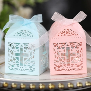 Detail of laser-cut cross pattern candy boxes with organza ribbons in light blue and pink