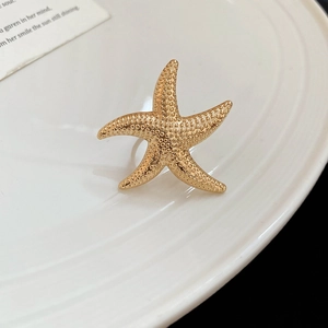 Detailaufnahme des goldenen Seestern-Rings mit strukturierter Oberfläche auf Keramik