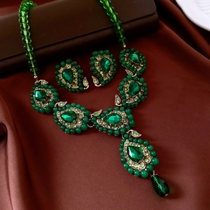 Détails macro de l'ensemble bijoux goutte avec pierre verte sur tissu en soie brune