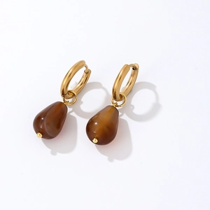 Macro shot of gold hoop earrings with translucent dark brown teardrop stones on white surface