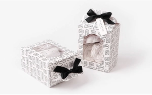 Detail of white gift boxes with black ribbon bows and clear window showing sweet patterns