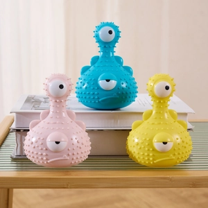 Close-up of three colorful monster dog toys with textured surfaces on a shelf