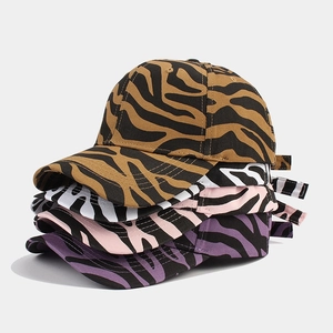 Detailed stack of cow print baseball caps in brown, white, pink, and purple canvas