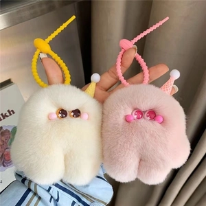 Close-up of cute plush monster keychains in pink and off-white with fluffy texture