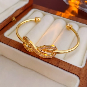 Macro detail of gold plated infinity bow bracelet with micro-set cubic zirconia stones