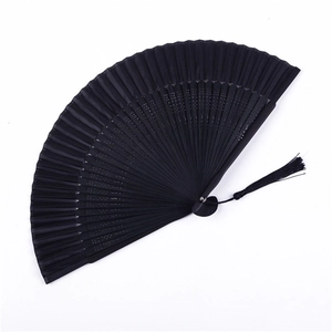 Detail of a black folding fan with hollowed patterns and a silk tassel pendant