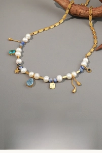 Detail of freshwater pearl necklace with blue stones and gold stainless steel charms
