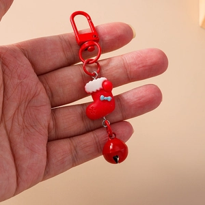 Close-up of a red Christmas stocking keychain with blue bow and matching metal bell